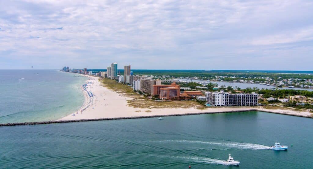 Aerial view of Gulf Shores with sandy beaches, bustling waterfront, and residential areas highlighting how easy transportation in gulf shores is for visitors exploring the area